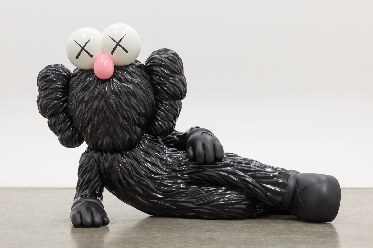 Sculpture of a comic character lying on its side, supported on one side, with black fur, a pink snub nose, and X-shaped eyes. KAWS | TIME OFF, 2021 | Private Collection © KAWS | Photo: courtesy KAWS Studio