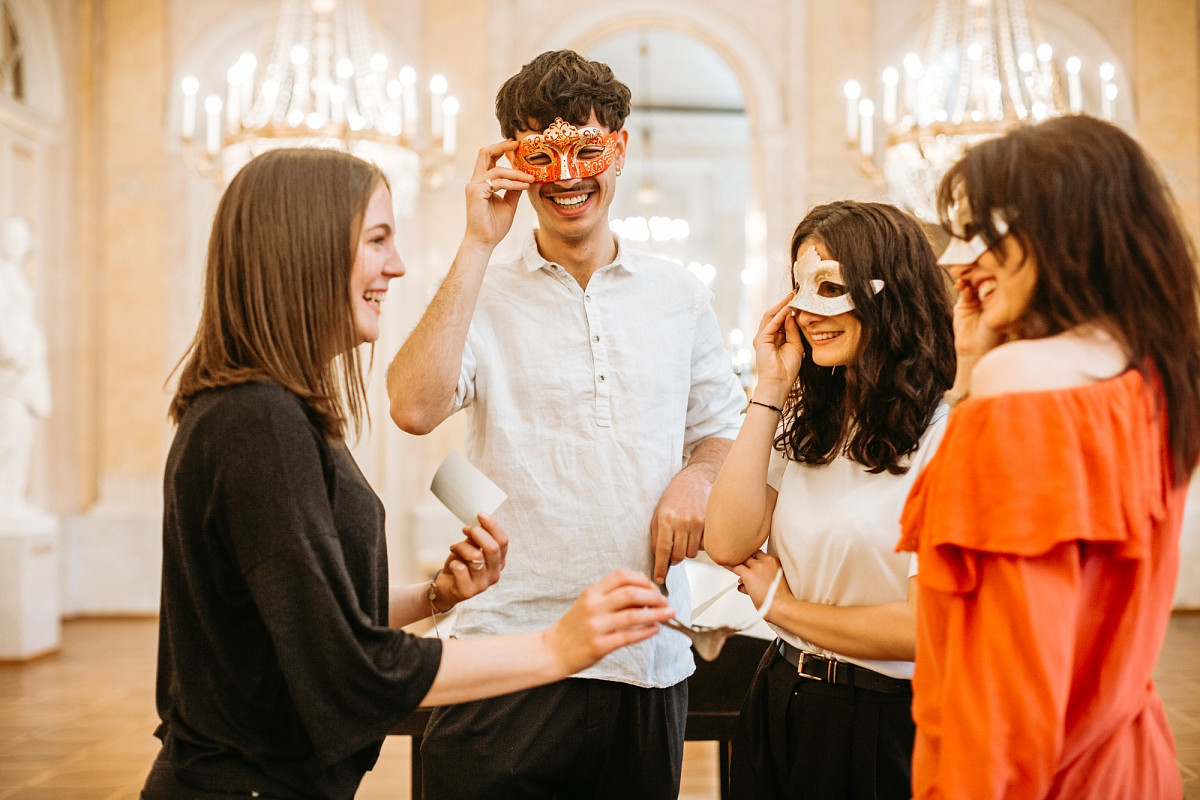 A group of friends, some with a mask over their eyes - all smiling. A woman holds a piece of paper in her hand. | Photo © Mystery Makers/Philipp Lipiarski