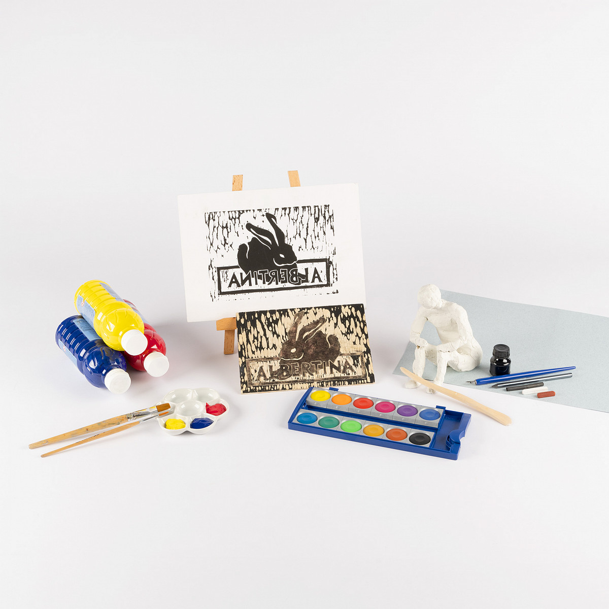 Several painting utensils: In the center a stamp with the motif of the Dürer hare and the writing “Albertina” above it. Next to it, brushes and paints. | Photo © ALBERTINA Fotostudio