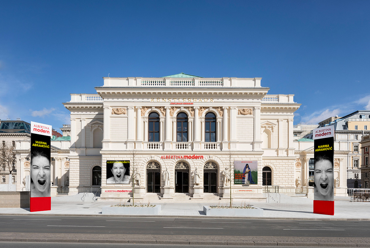 Exterior view of the building during the day with posters advertising the current exhibitions on the outer wall.