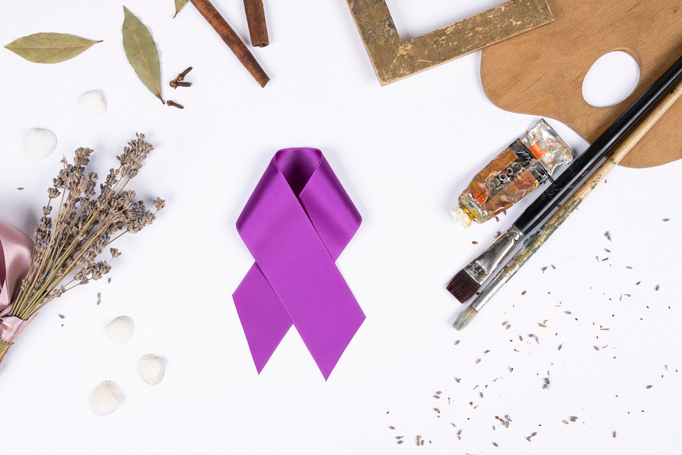 A purple bow on a white background, surrounded by decorative accessories such as paints, brushes, a picture frame and lavender | Photo © ALBERTINA Fotostudio