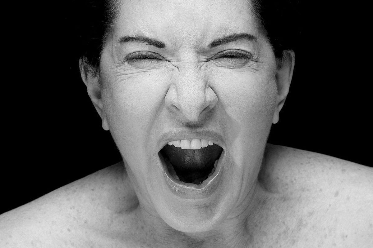 Black and white portrait of the artist, showing her screaming with her mouth open. Credit: Marina Abramović | Four Crosses, 2019 | Courtesy of the Marina Abramović Archives | © Courtesy of the Marina Abramovic Archives / Bildrecht, Vienna 2025