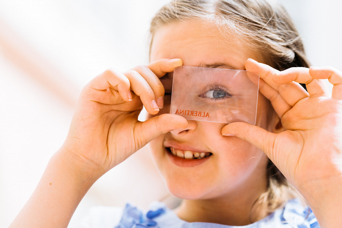 Kind schaut durch eine Glasscheibe mit der Aufschrift ALBERTINA | Foto © Marko Mestrovic