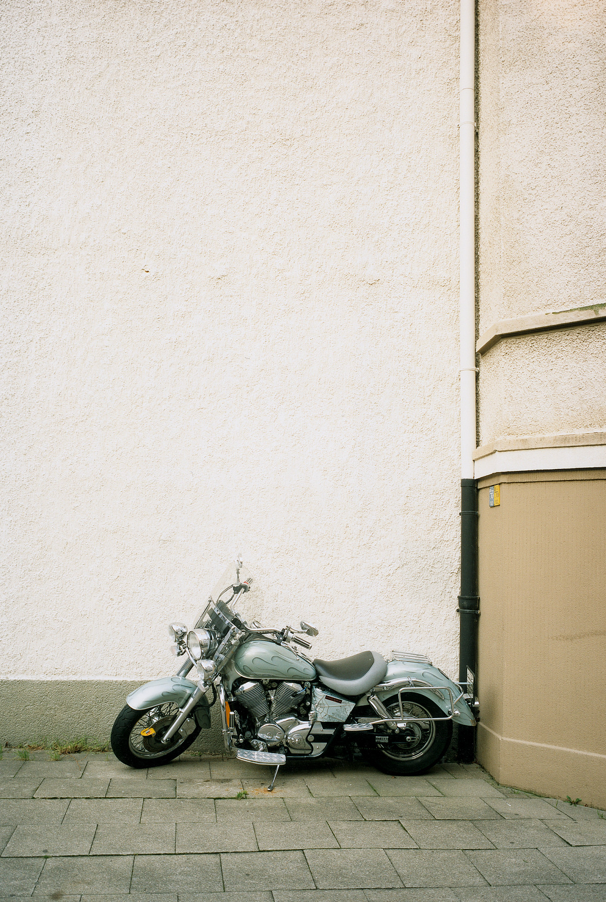 A gray motorcycle in front of a beige house.