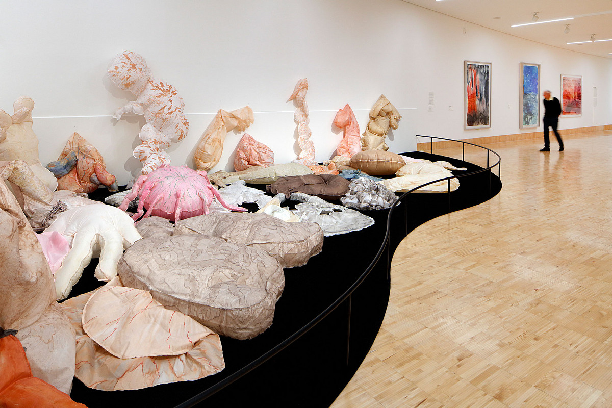View of the exhibition hall with an inflation sculpture on the floor and abstract works on the walls.