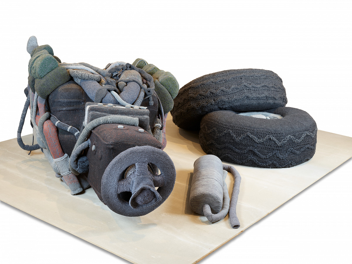 A car engine, two car tires stacked on top of each other, and an exhaust pipe. All crocheted.