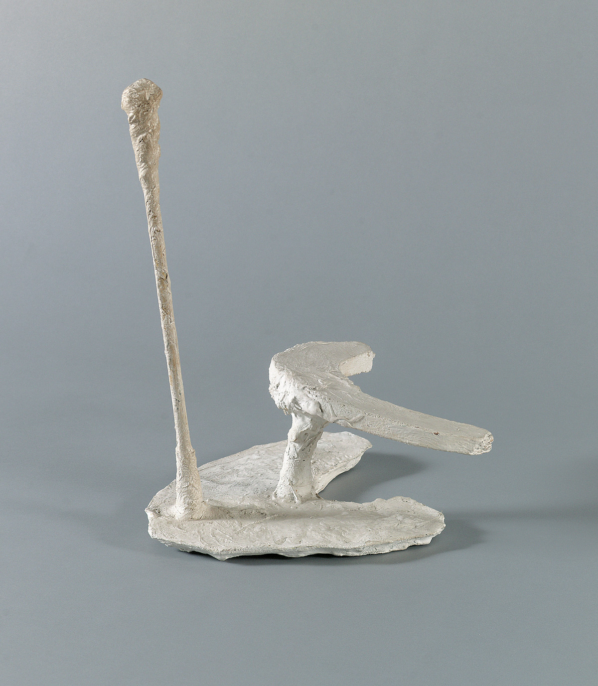 White sculpture with a rod and a boomerang protruding upwards.