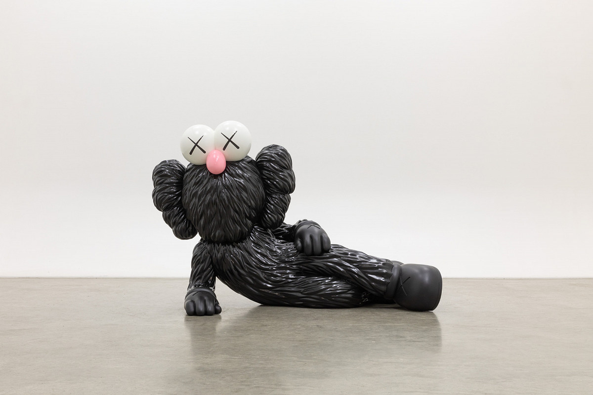 Sculpture of a comic character lying on its side, supported on one side, with black fur, a pink snub nose, and X-shaped eyes. Credit: KAWS | TIME OFF, 2021 | Private collection © KAWS |Photo: courtesy KAWS Studio