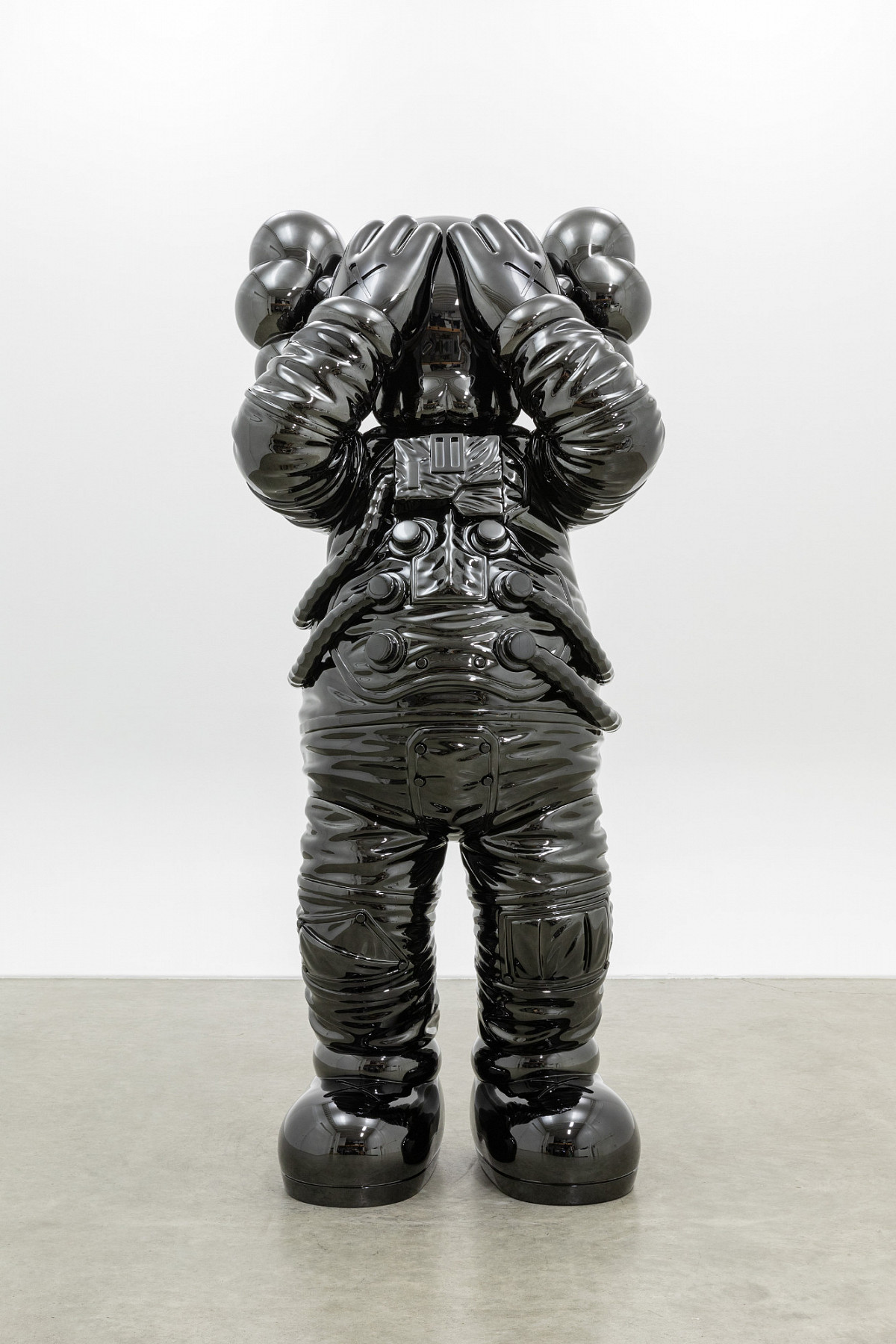 Sculpture of a black comic book character in a space suit, holding his hands in front of his eyes.
