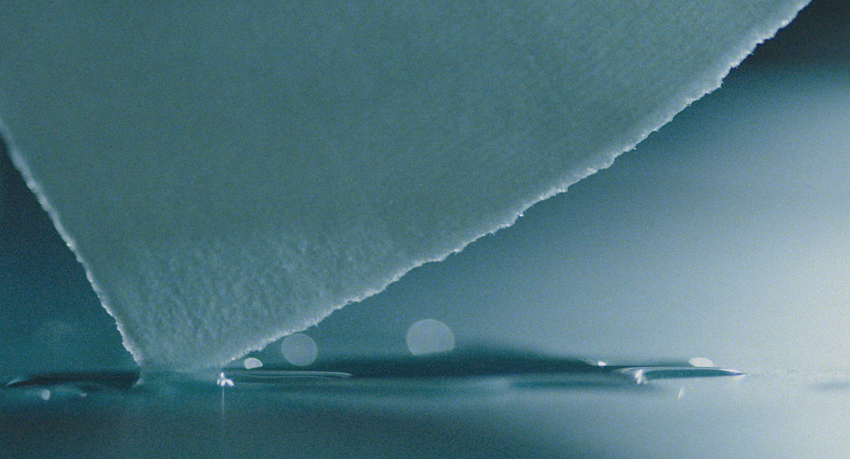 The tip of a piece of paper dips into the water.