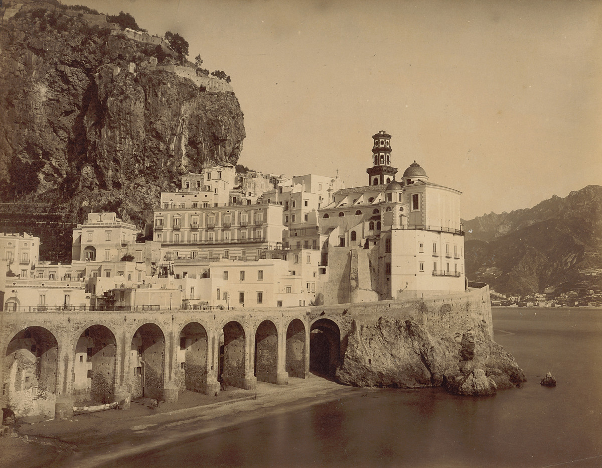 The coastal town of Atrani, with closely built houses on the hillside and the sea in the foreground.